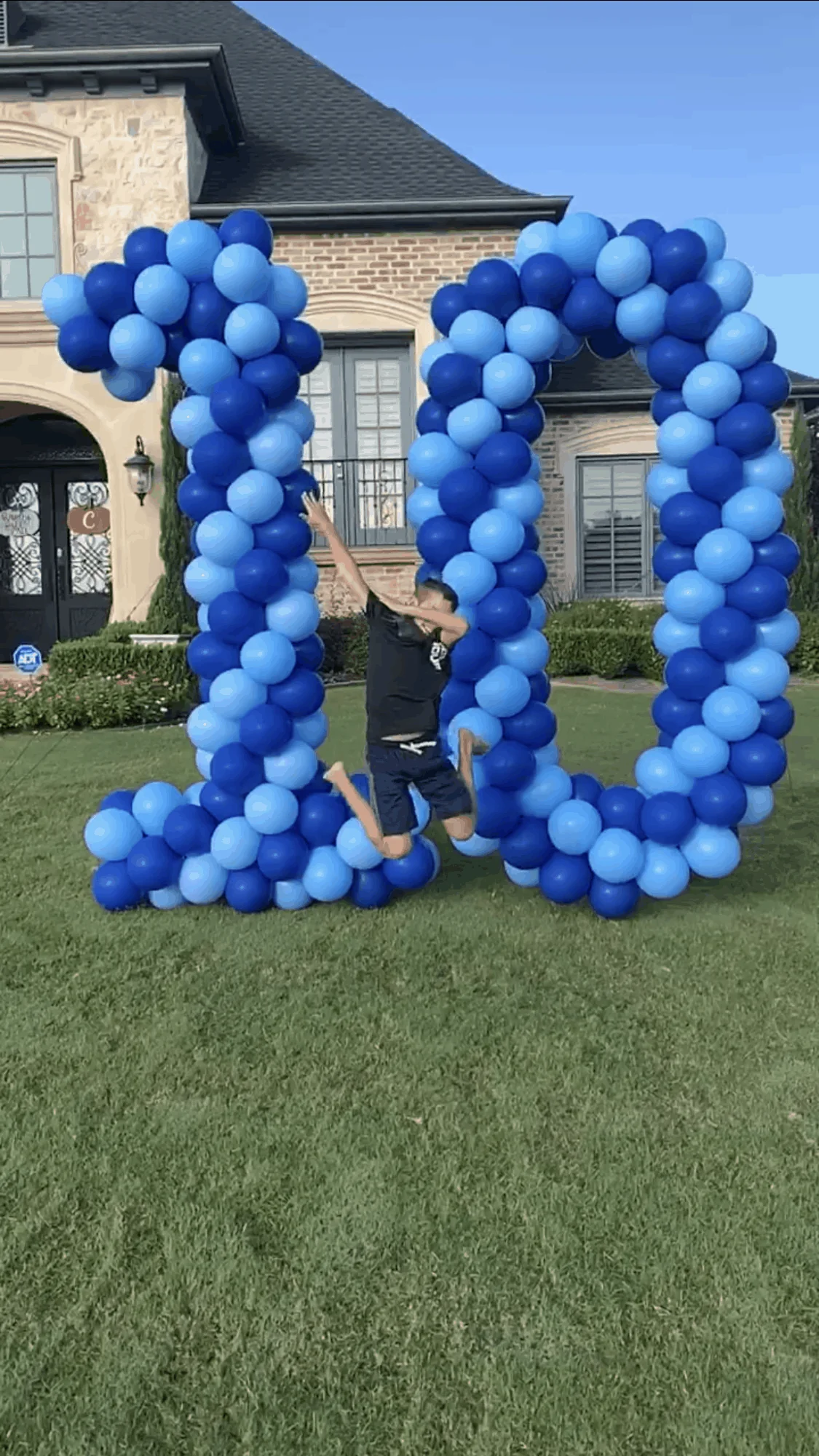 a man jumping in the air in front of a large number made of balloons