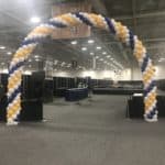 Gold, black and white balloon arch inside an event venue