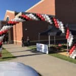 Red, black and white balloon arch outside an entrance