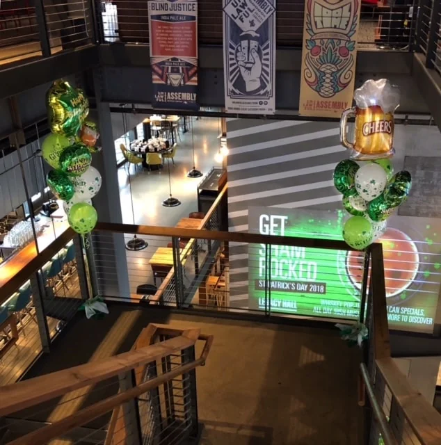 Green St. Patrick’s Day balloon bouquets beside an indoor staircase
