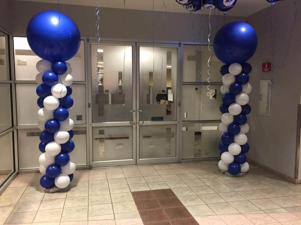 Blue and white spiral balloon columns beside an entrance