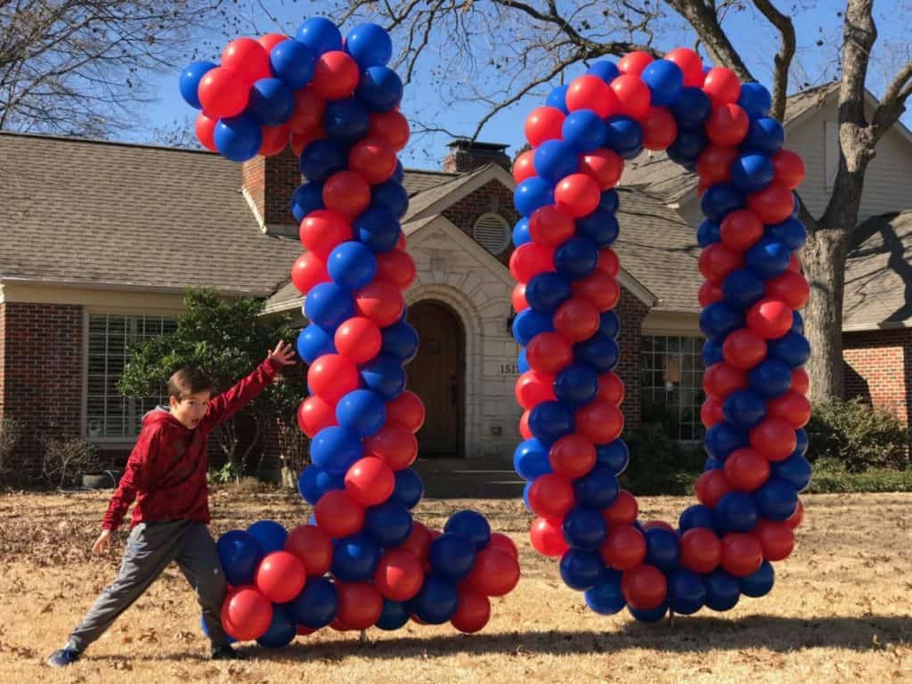 Red and blue balloon numbers 10 displayed in a front yard