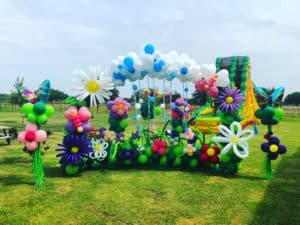 a balloon arch with flowers and balloons on grass