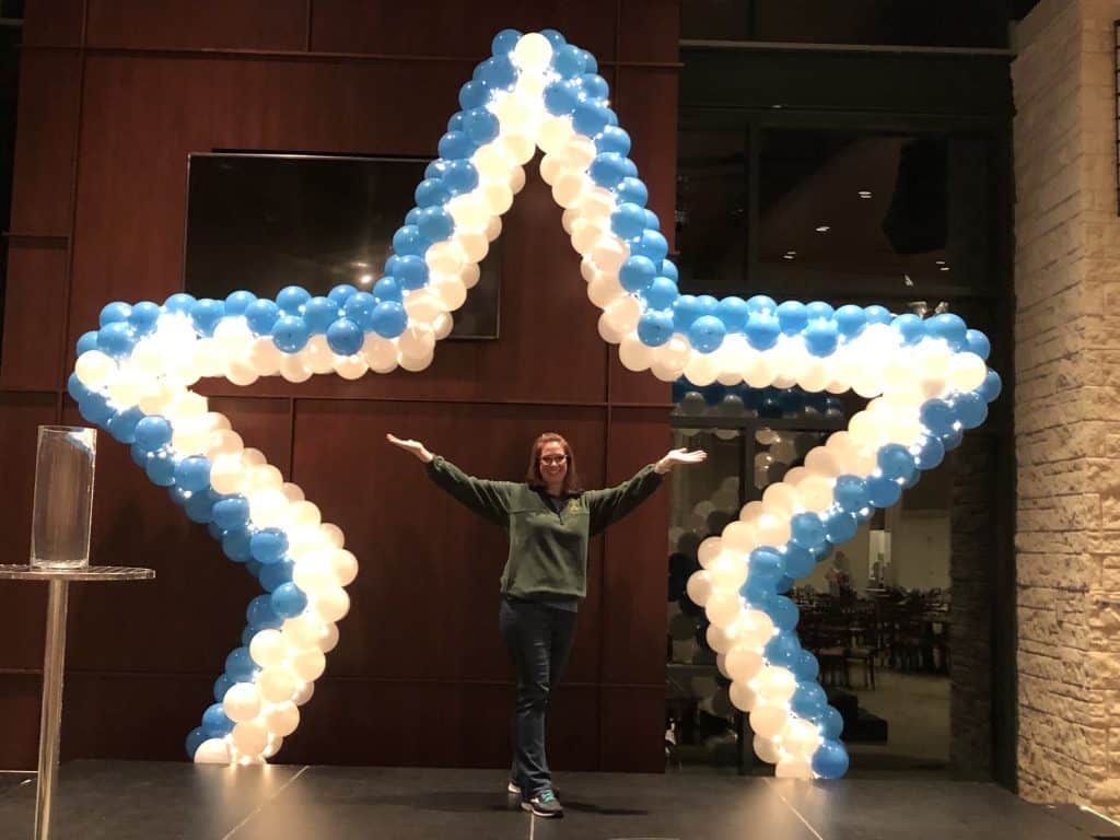a woman standing in front of a star shaped balloon arch